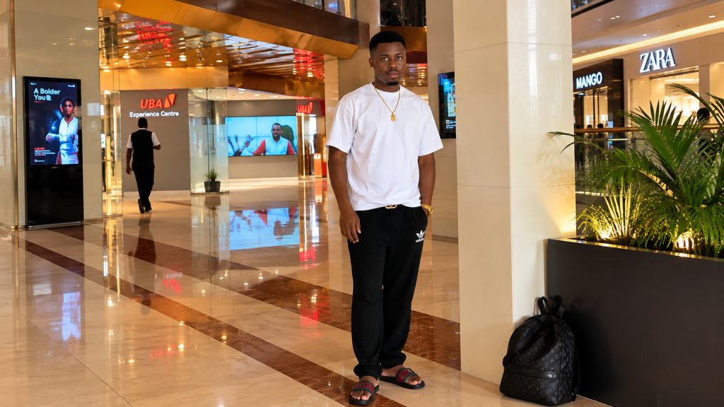 Prince Dumebi Micheal standing inside a modern shopping mall.