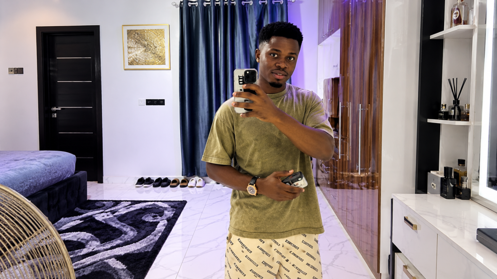 Prince Dumebi Micheal taking a mirror selfie in a modern interior.